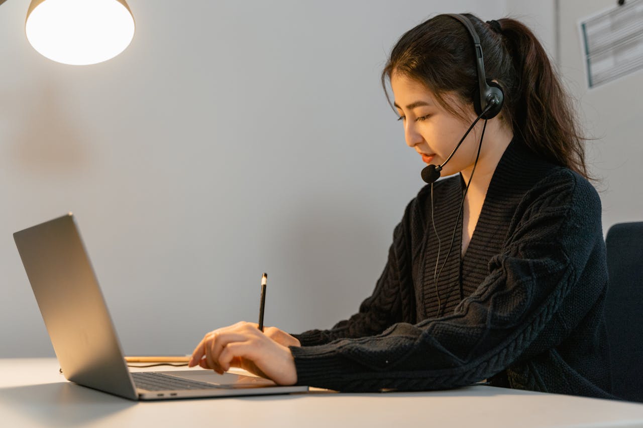 Crafting Captivating Headlines: Your awesome post title goes here Focused call center agent working on a laptop with headphones. Customer service professional in an office setting.