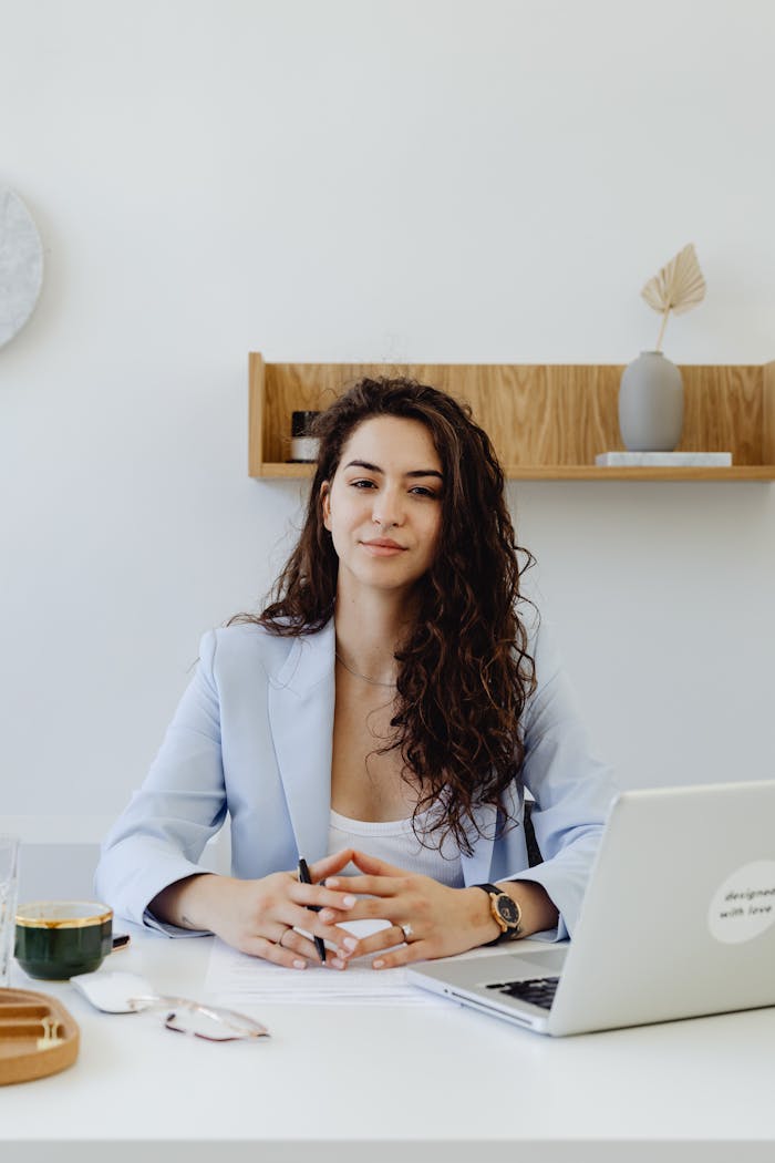Mastering the First Impression: Your intriguing post title goes here Portrait of a confident businesswoman sitting at a desk with a laptop in a modern office.